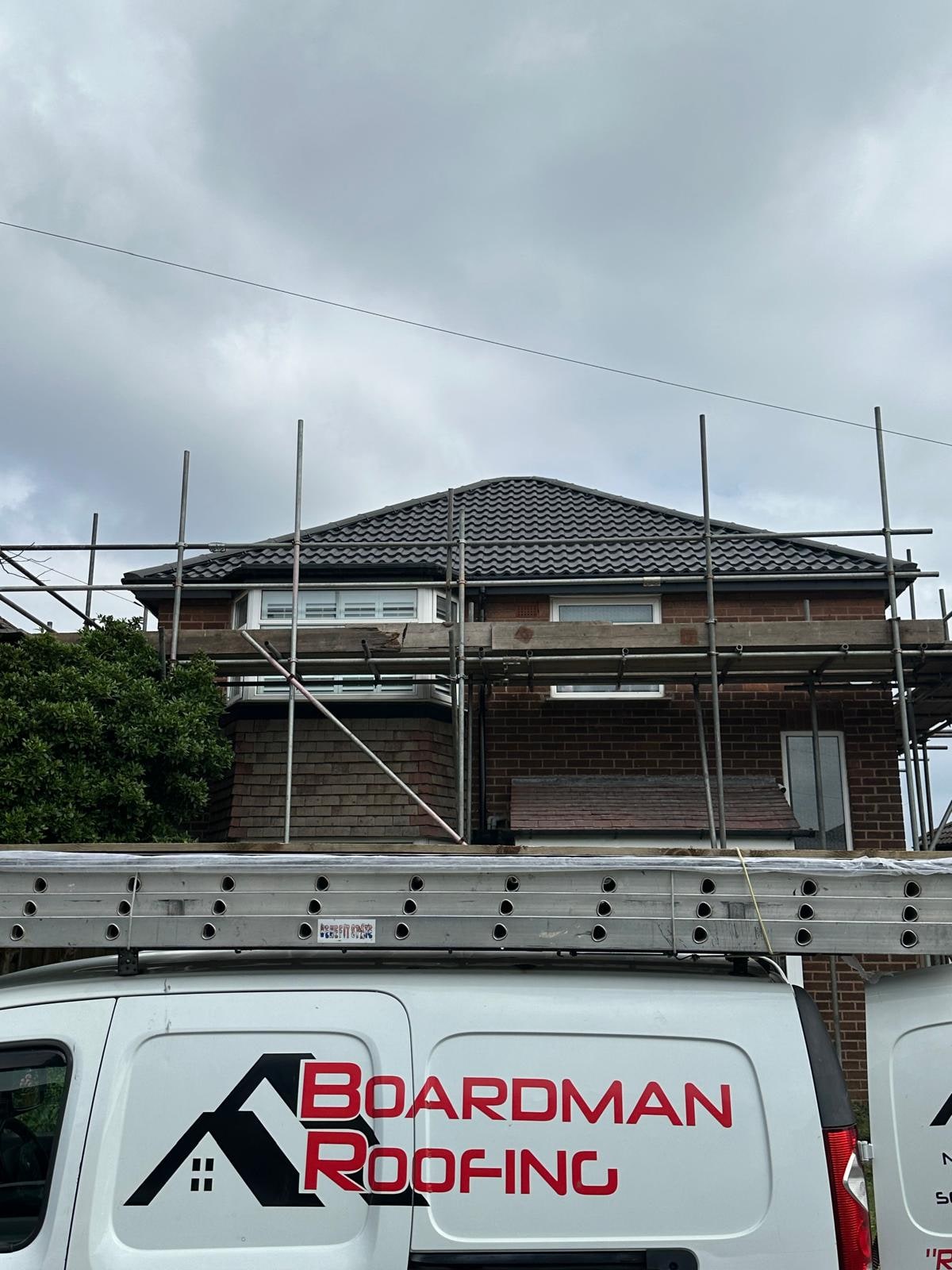 The Boardman Roofing van outside a scaffolded bungalow with a new tiled roof