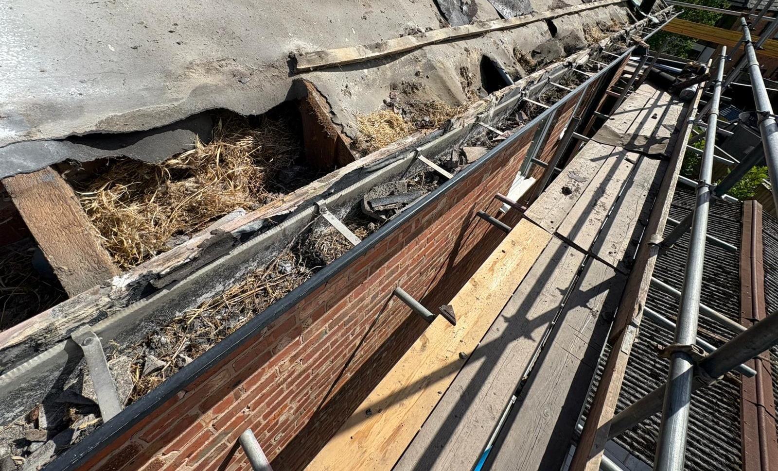 An old roof edge with a gutter full of debris and failed mortar