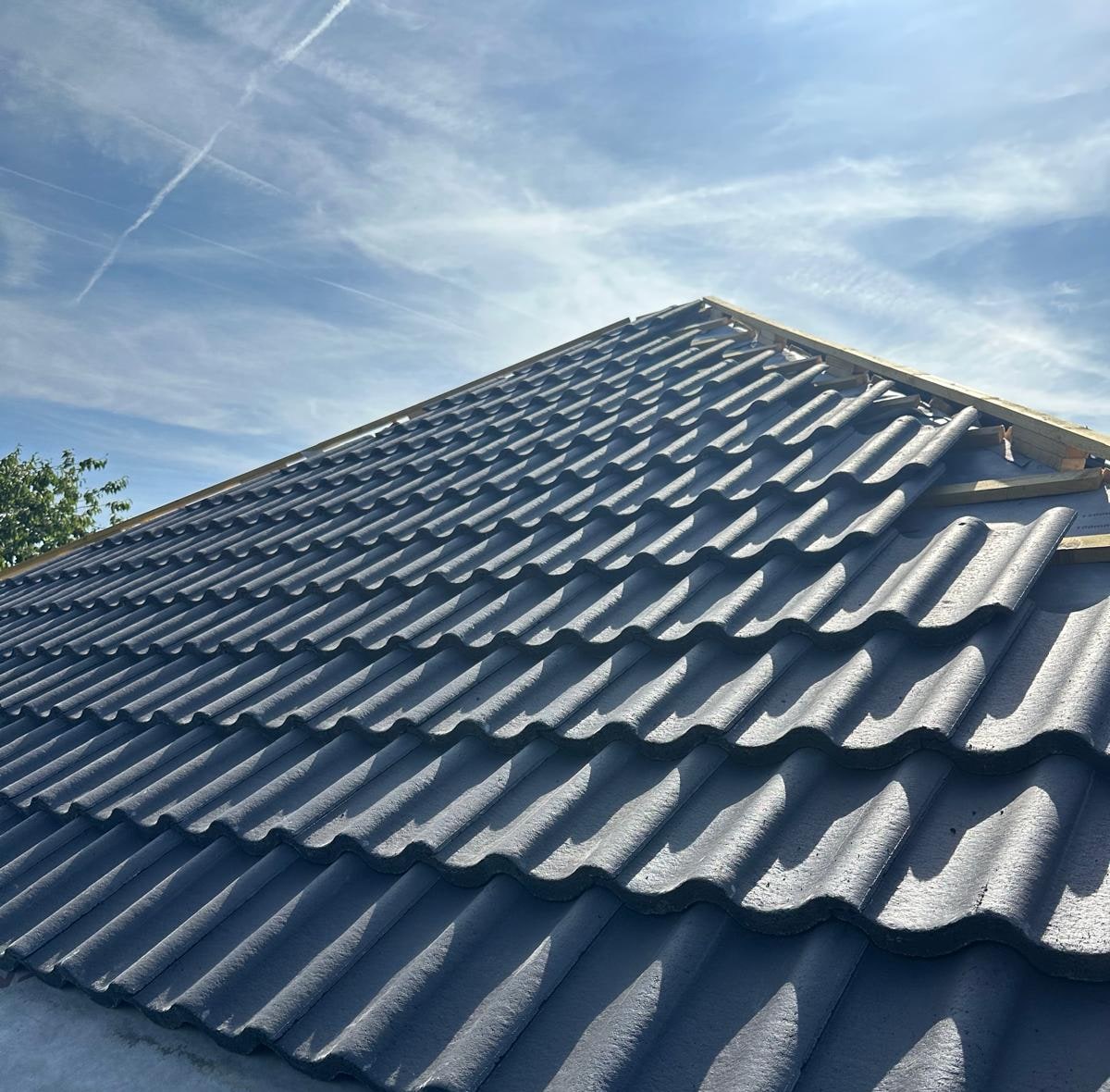 Grey tiles being laid over breather membrane and timber battens